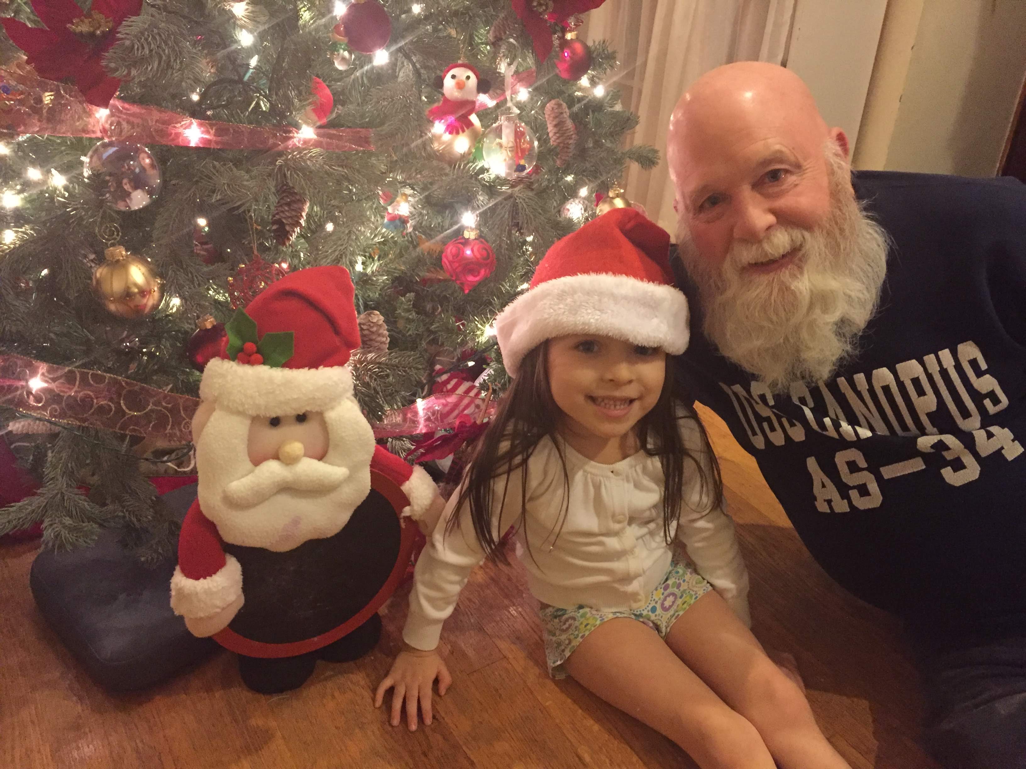 Tom as Santa with a child by the Christmas tree